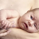 IN*Portrait bébé triste dans les bras de sa mère, torse nu, intérieur